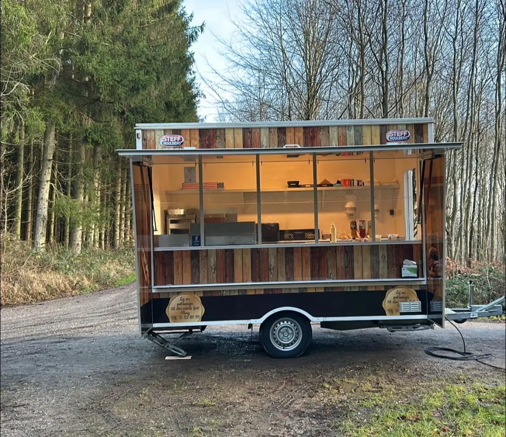 Pølsevognen på en skovvej, oplyst indefra